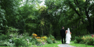Bride and Groom walking down cobblestone trail near woods.