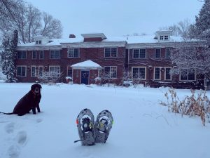 Snowshoes, dog, and Outing Lodge exterior.